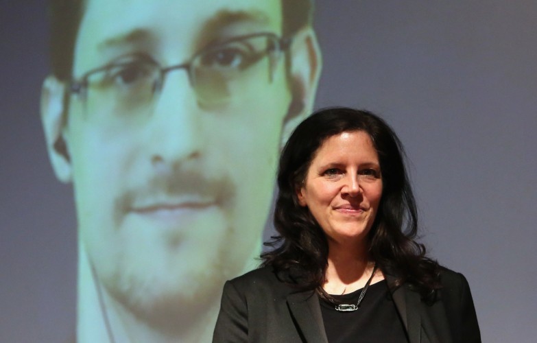 BERLIN, GERMANY - DECEMBER 14: Filmmaker Laura Poitras stands on the stage as former National Security Agency (NSA) contractor turned whistleblower Edward Snowden is seen on a video conference screen during an award ceremony for the Carl von Ossietzky journalism prize on December 14, 2014 in Berlin, Germany. Poitras, Snowden and journalist Glenn Greenwald (the latter two in absentia) were awarded the prize by the International League for Human Rights for having 'put their personal freedom on the line to expose abuse of power' by Germany and the United States in their revelations of the extent of government surveillance on ordinary citizens in the name of 'national security' in the wake of terrorist attacks. The prize is named for journalist and Nobel Peace Prize winner Ossietzky, who died from complications from being held as a dissident in a Nazi concentration camp. A bid to allow Snowden, who has temporary asylum in Moscow, to testify in Berlin before an NSA parliamentary inquiry is ongoing. (Photo by Adam Berry/Getty Images)
